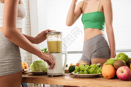 减肥季节新鲜自由活力年轻闺蜜在家用榨汁机背景