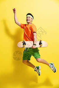 愉悦拿着滑板跳跃的青年男人图片