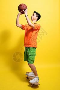 垂吊着的多面金属球滑着滑板投篮的青年男人背景