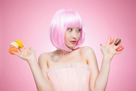 东亚粉色彩色图片看着手指夹满马卡龙的时尚女孩图片