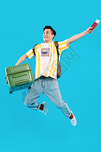 拎着行李箱跳跃的年轻男人图片