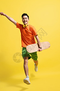 帅哥拿着滑板跳跃的快乐青年男人图片
