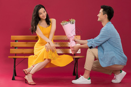 坐着伸手的女孩青年夫妇坐着东亚浪漫的青年男人给女朋友送花背景