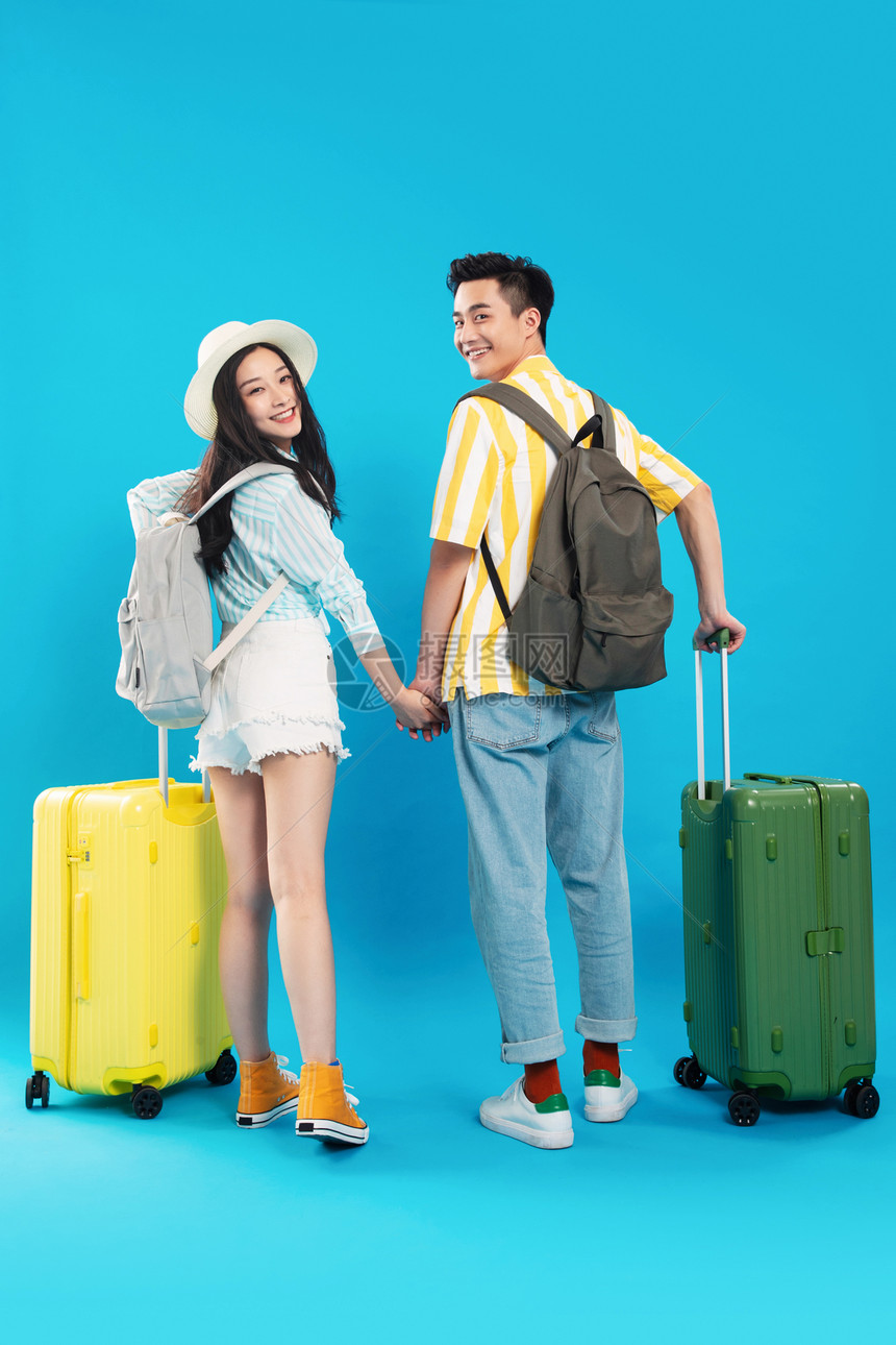 短裤垂直构图绿色快乐的青年情侣推着行李箱去旅游图片