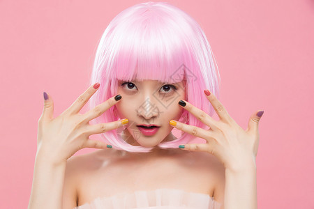 站着粉色背景头和肩膀展示彩色指甲油的时尚年轻女人图片