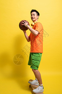 拿着篮球滑着滑板的青年男人图片