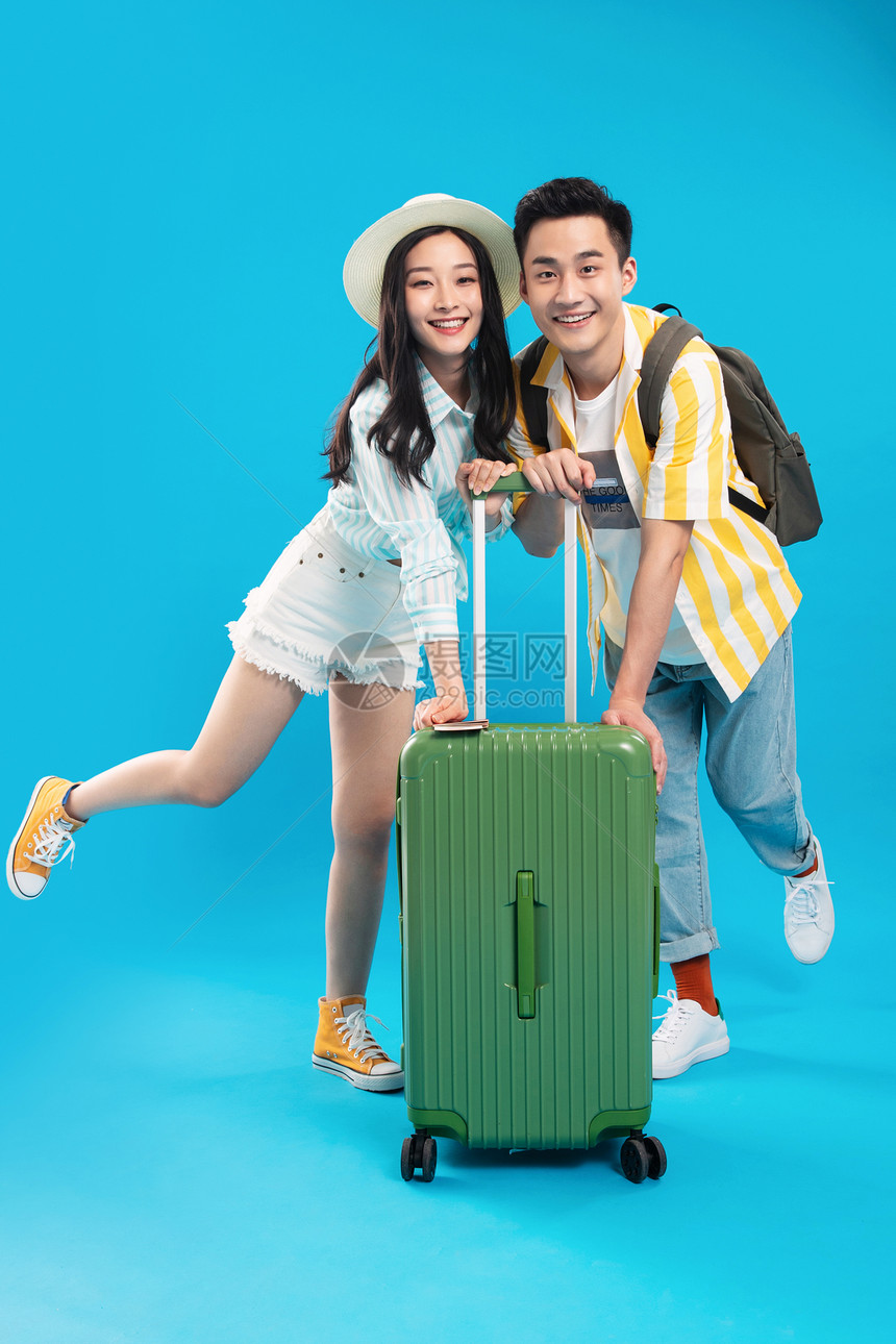 快乐青年情侣一起推着行李箱去旅游图片