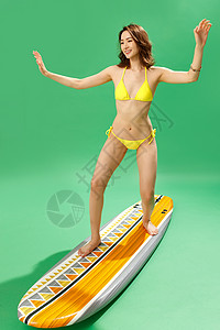 站在冲浪板上冲浪的比基尼美女图片