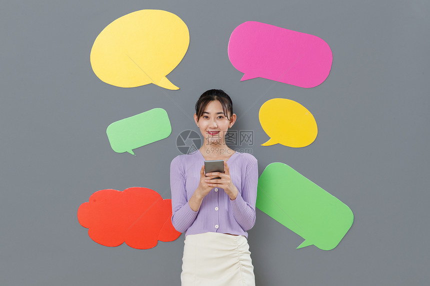 青年文化东亚色彩鲜艳拿着手机站在对话框前面的年轻女孩图片