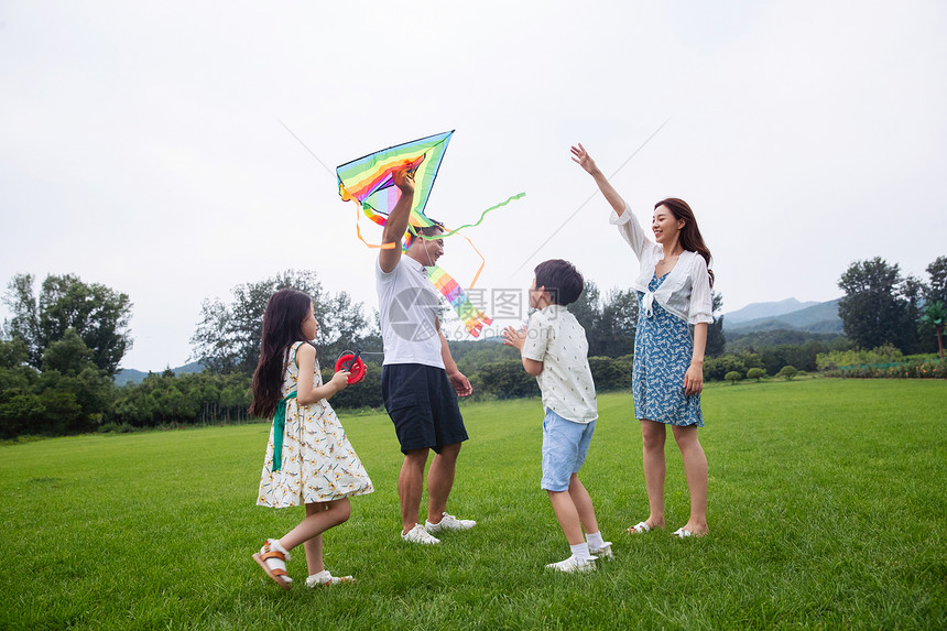 夏天生态旅游水平构图快乐的一家四口在草地上放风筝图片