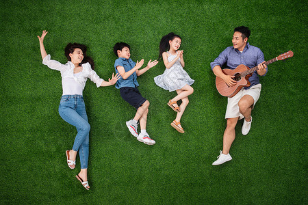 三个小孩在唱歌青年人侧卧青年女人幸福的一家四口在草地上唱歌背景