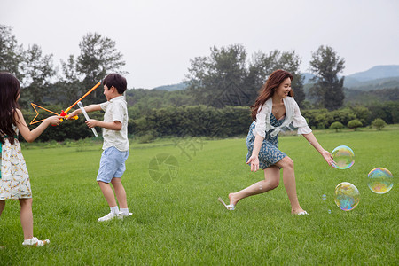 8到9岁女孩儿童妈妈带着两个孩子在草地上快乐玩耍图片