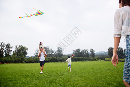 飞线兴奋短裤青年女人快乐的一家四口在草地上放风筝背景