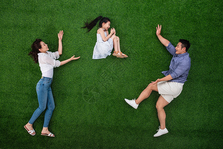 做父亲的靠山白昼妻子高举手臂草地上做游戏的一家三口背景