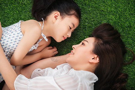 聊天表情贴纸的孩子幸福的母女面对面躺在草地上背景