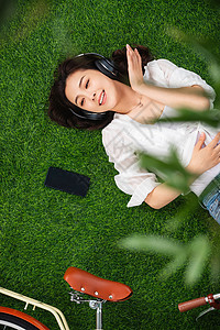 无忧无虑选择对焦摄影躺在草地上听音乐的青年女人图片