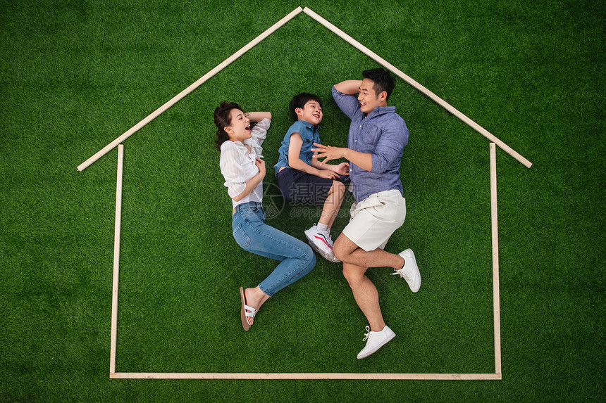 人爱草坪快乐的一家三口躺在草地上的房子轮廓里玩耍图片