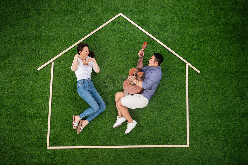 青年夫妇郊游想象青年伴侣躺在草地上的房子轮廓里唱歌跳舞图片