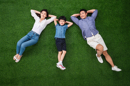 牛仔裤双亲家庭童年幸福的一家三口躺在草地上图片