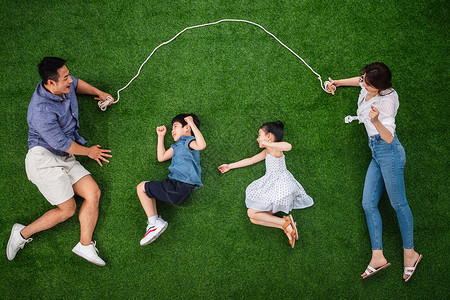 公园亚洲成一排快乐的一家四口在草地上跳绳高清图片