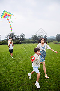 线盘轮男孩东亚选择对焦快乐的一家四口在草地上放风筝背景