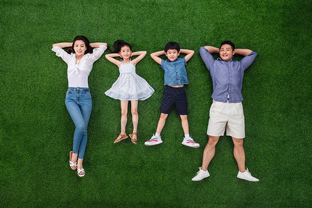 周末活动8到9岁两个孩子的家庭幸福的一家四口躺在草地上图片