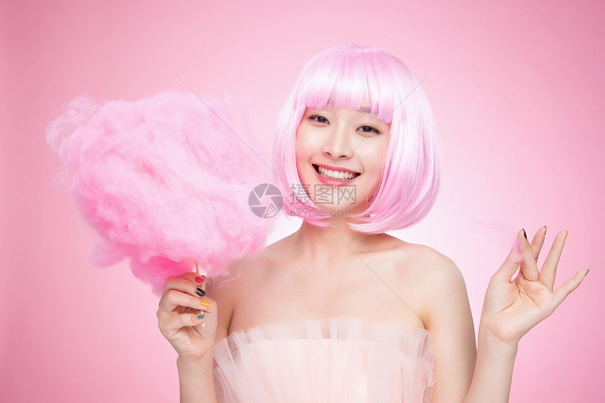 拿着粉色棉花糖的时尚年轻女孩图片