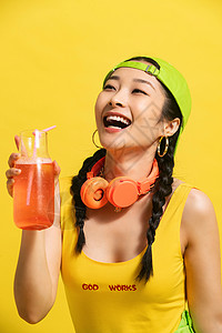 金色果汁飞溅耳机黄色背景青年文化喝饮料的青年女人背景