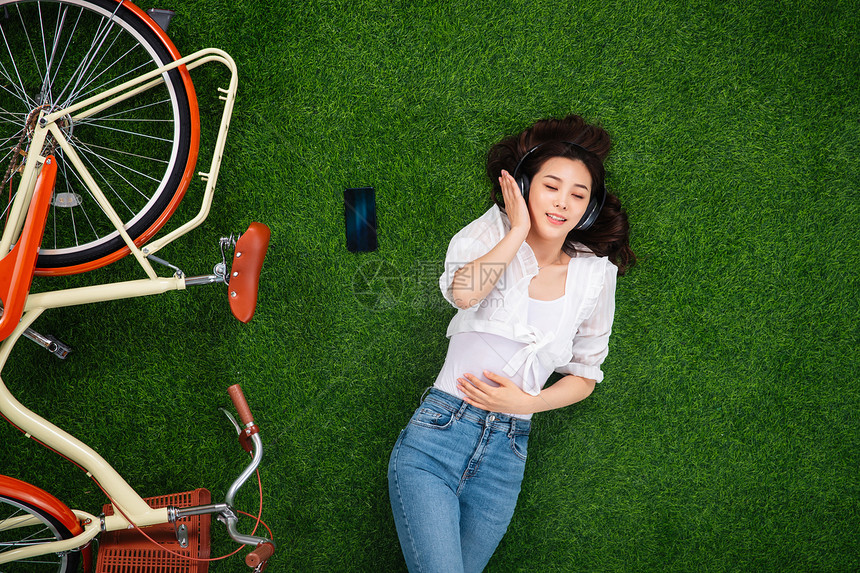 躺在草地上听音乐的年轻女人图片