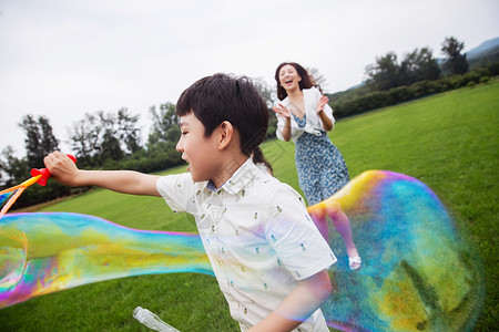 乐趣亚洲夏天快乐的母子在草地上玩耍吹泡泡图片