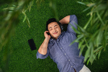 躺在草地上听音乐的青年男性图片