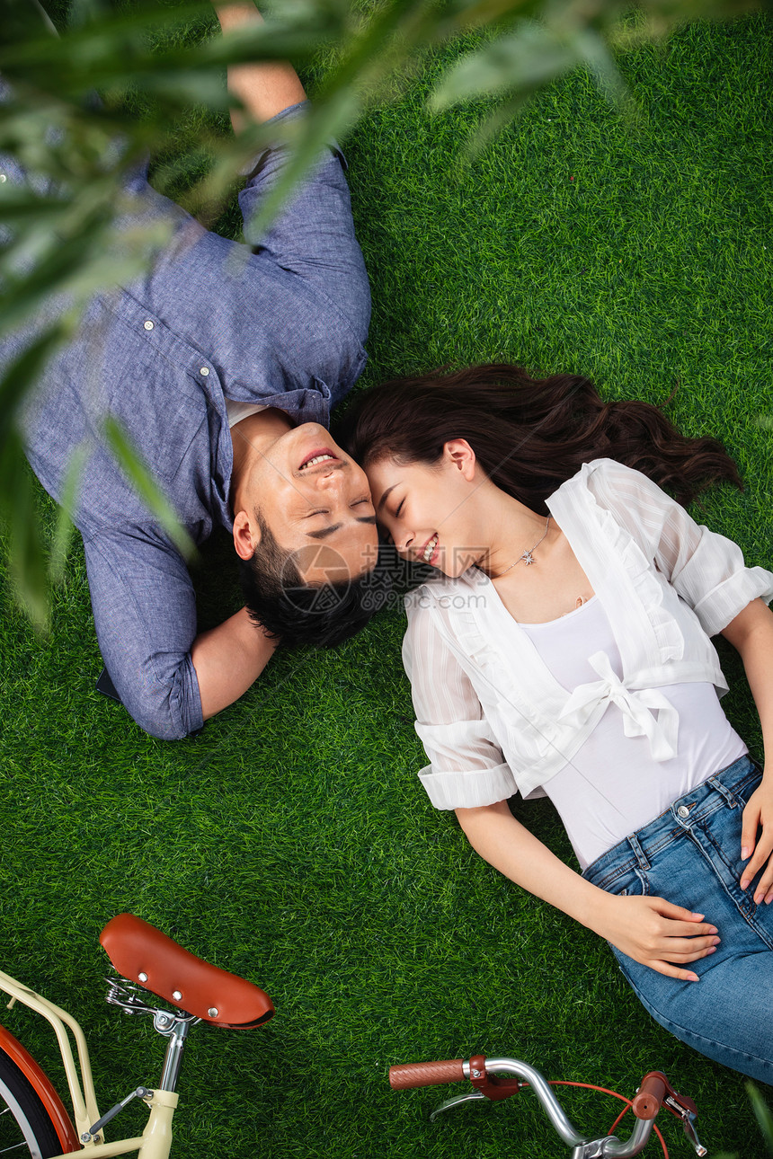 逃避现实妻子仅成年人幸福的青年伴侣躺在草地上享受亲密时光图片