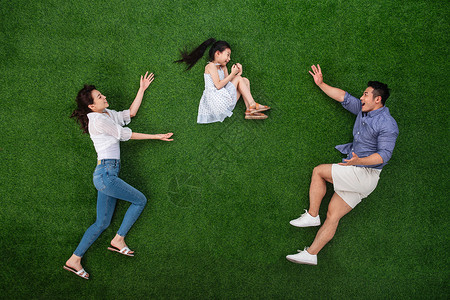 青年夫妇旅行快乐草地上做游戏的一家三口图片