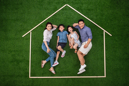 房地产开盘活动两个孩子的家庭陪伴度假快乐的一家四口躺在草地上的房子轮廓里背景