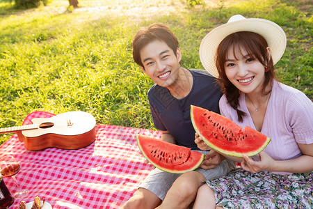 在草地上吃西瓜的幸福情侣图片