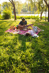 日光户外自然坐在公园里弹吉他的幸福情侣图片