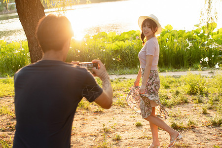 女孩举着荷叶照相水平构图夏天幸福情侣在公园里拍照背景