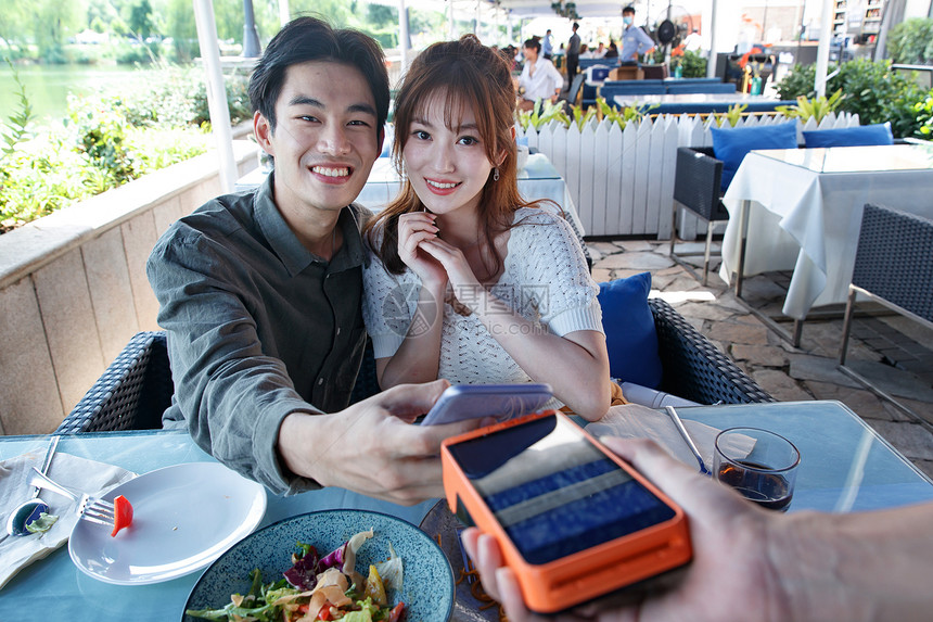 放松彩色图片亚洲年轻情侣在餐厅用手机付款图片