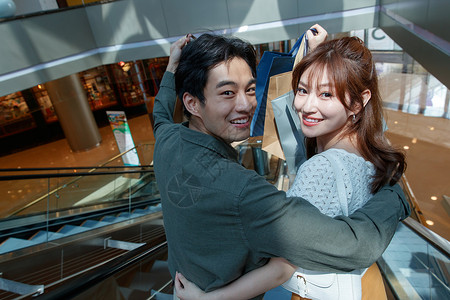 青年夫妇乐趣城市在商场里乘电梯的幸福情侣图片