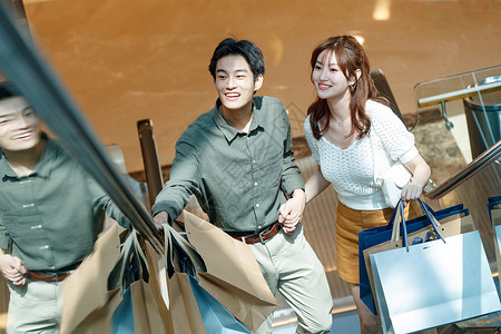 夫妇手牵手爱在商场里乘电梯的幸福情侣图片