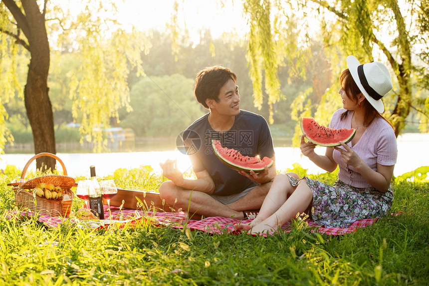 青年情侣坐在公园里吃西瓜图片