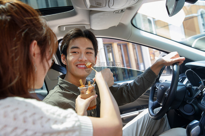 两个人交通方式愉悦坐在汽车里的青年情侣吃东西图片