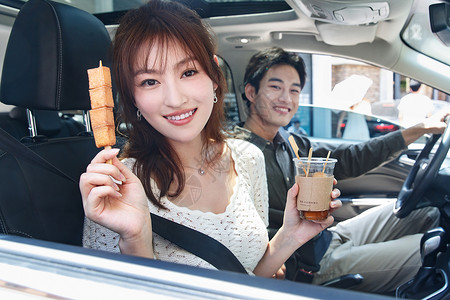 东方人微笑水平构图坐在汽车里的青年情侣吃东西图片