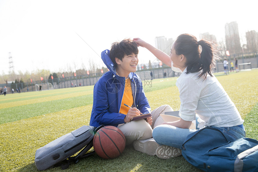 坐着草坪青年大学生在校园里学习图片