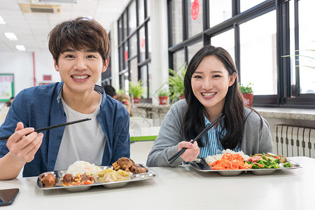 看着镜头情侣20多岁注视镜头青年人大学生在食堂里用餐背景