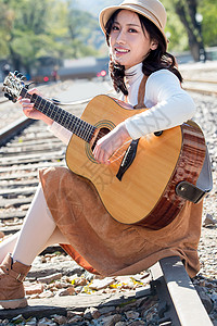 怀旧青年女人坐在铁路边弹吉他图片