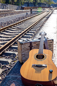 复古郊游环境铁轨旁边的吉他和旅行箱图片