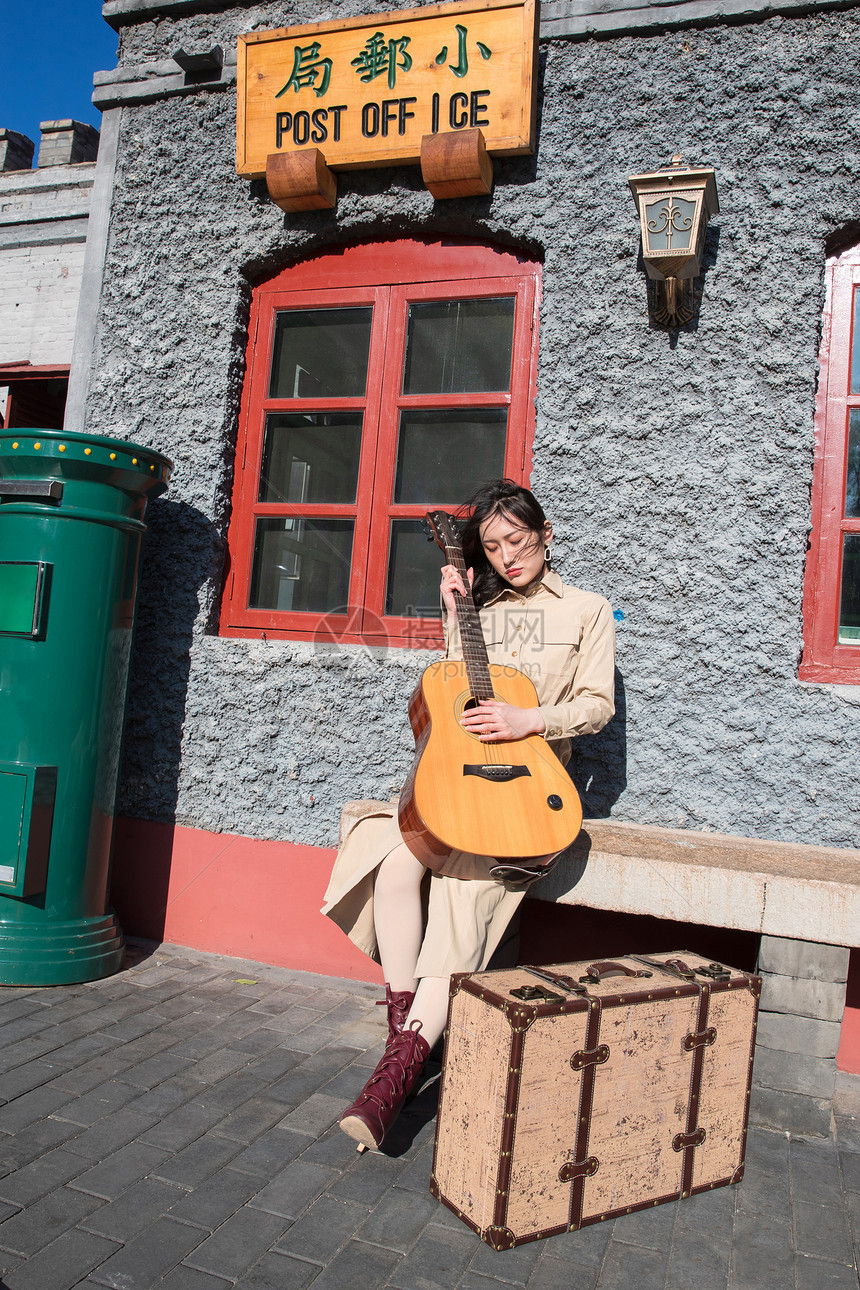20多岁非都市风光弹奏青年女人坐在户外弹吉他图片