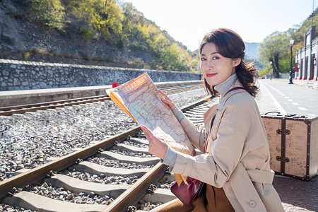 铁路地图青年女人坐在铁轨旁边看地图背景