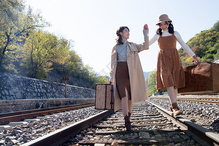 快乐休闲活动嬉戏的青年闺蜜手牵手走在铁轨上图片